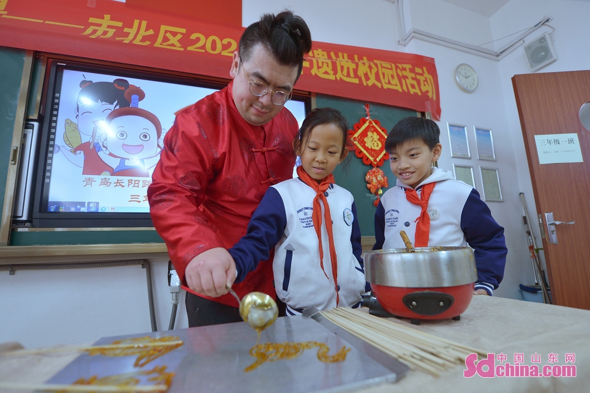 <br/>　　在山东省青岛市长阳路小学传统文化进校园活动上，学生在民间艺人指导下轮流体验糖画制作。<br/>