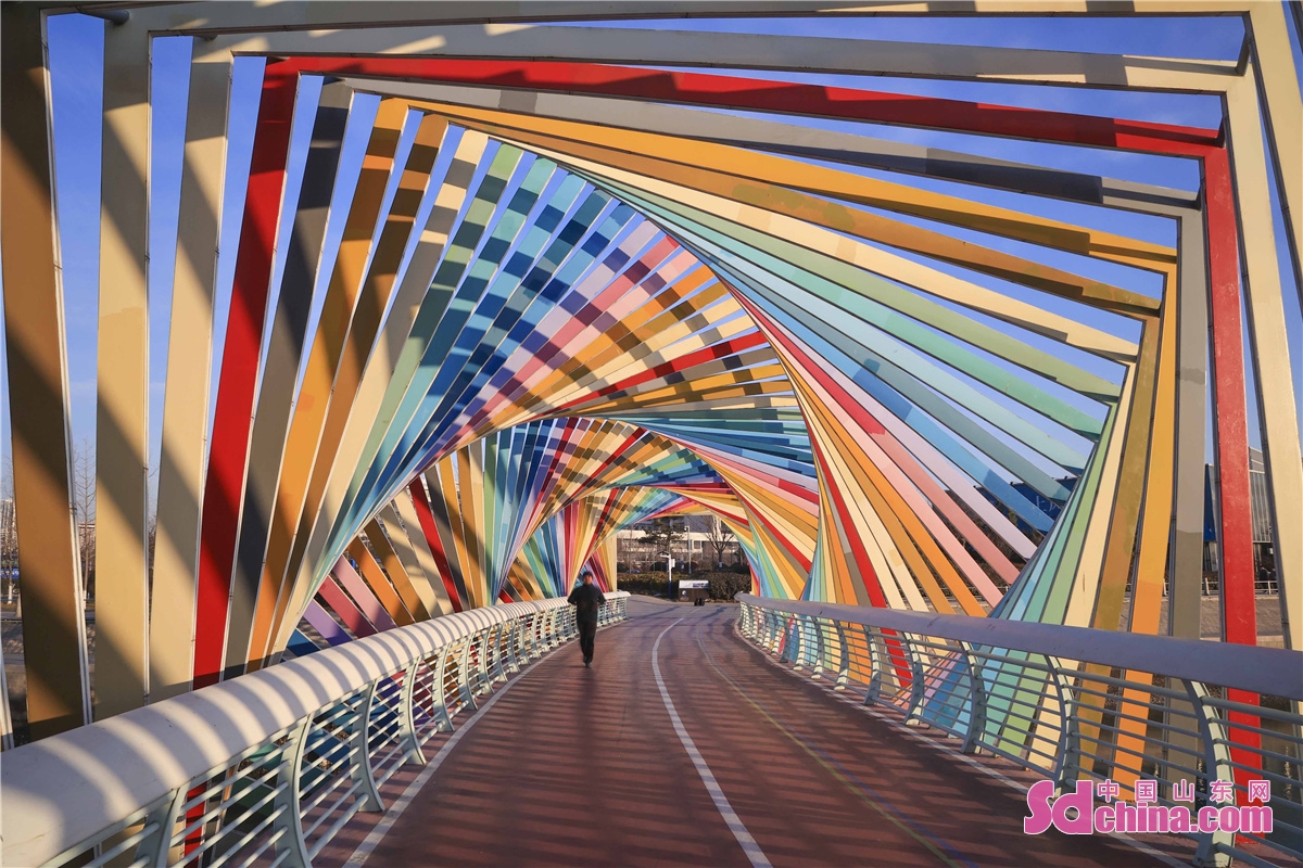 <br/>　　2021年12月28日，山东青岛西海岸新区唐岛湾畔的彩虹桥光彩夺目，宛如彩虹般铺展在蔚蓝色海面上。市民在彩虹桥上来来往往，感受着彩虹桥的绚丽缤纷和静谧温馨。(韩加君)<br/>