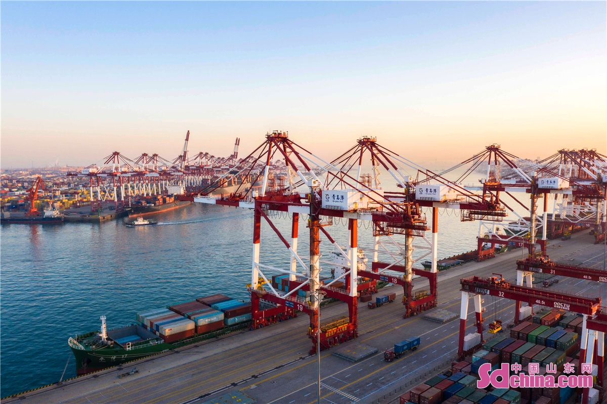 <br/>　　2021年12月31日清晨，山东港口青岛港前湾集装箱码头各个泊位上的集装箱船正在有序地装卸集装箱，港口一片繁忙景象。<br/>