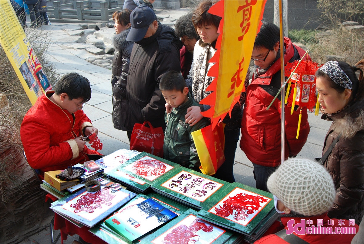 Wang Tao, inheritor of Jinan intangible heritage paper cutting, cuts window flowers for tourists in Baotu Spring Scenic Spot as the Spring Festival approaching.(Wang Ping)<br/>