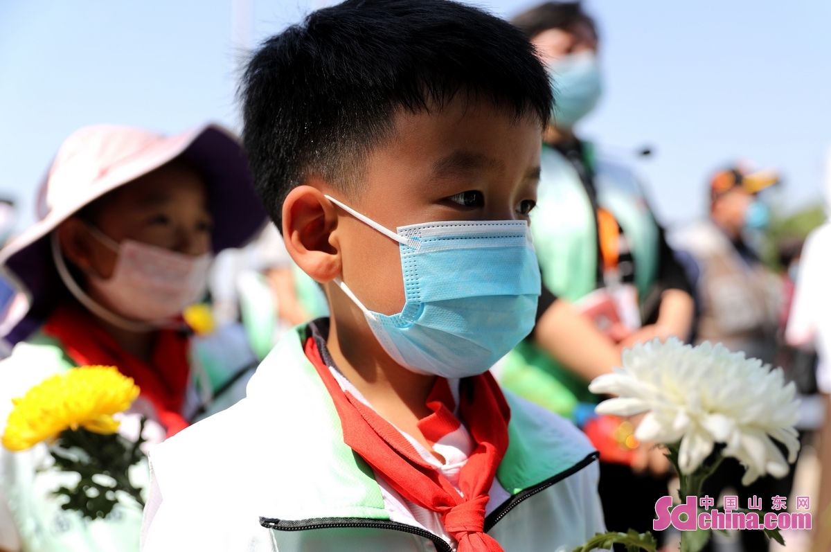 <br/>　　5月22日，在青岛城阳盐碱地稻作改良示范基地，一名小朋友在排队给袁隆平爷爷献花。(张进刚 摄)<br/>　　