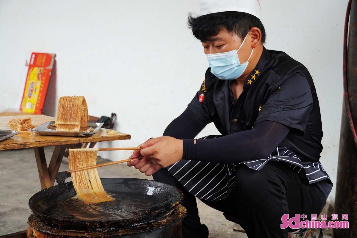 <br/> <br/>Zhao Yansen, the 5th generation inheritor of Huanggang Sanzi is making fried dough twist, an intangible cultural heritage of Heze City. First made in 1774, Huanggang Sanzi uses pure cottonseed oil and high-quality wheat powder as raw materials and goes through ten processes. It is golden in color and tastes crispy, slag-free and fragrant.<br/>
