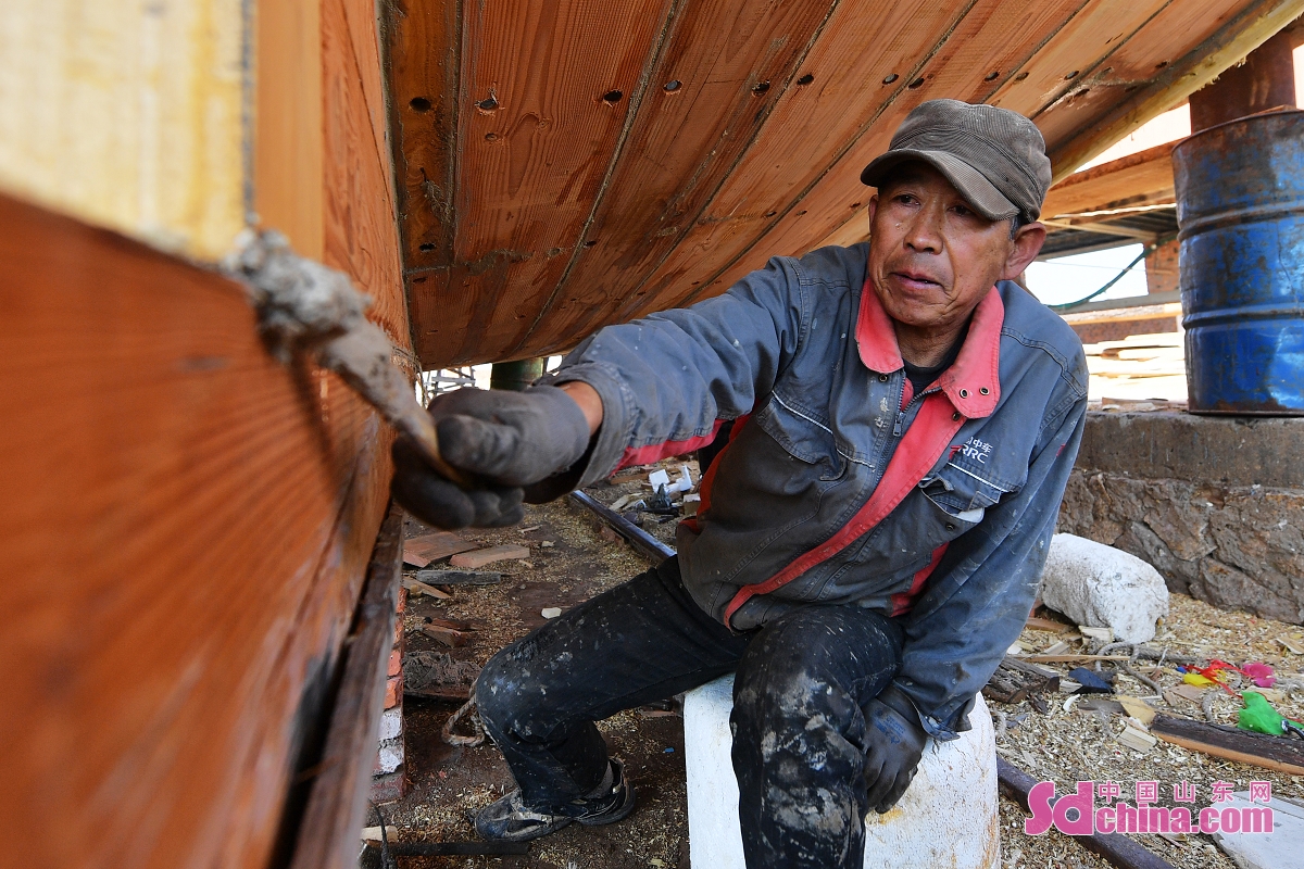 <br/>　　在山东省青岛市城阳区红岛街道一处木船制造厂，一名工匠师傅在为木船缝隙刮上腻子。<br/>