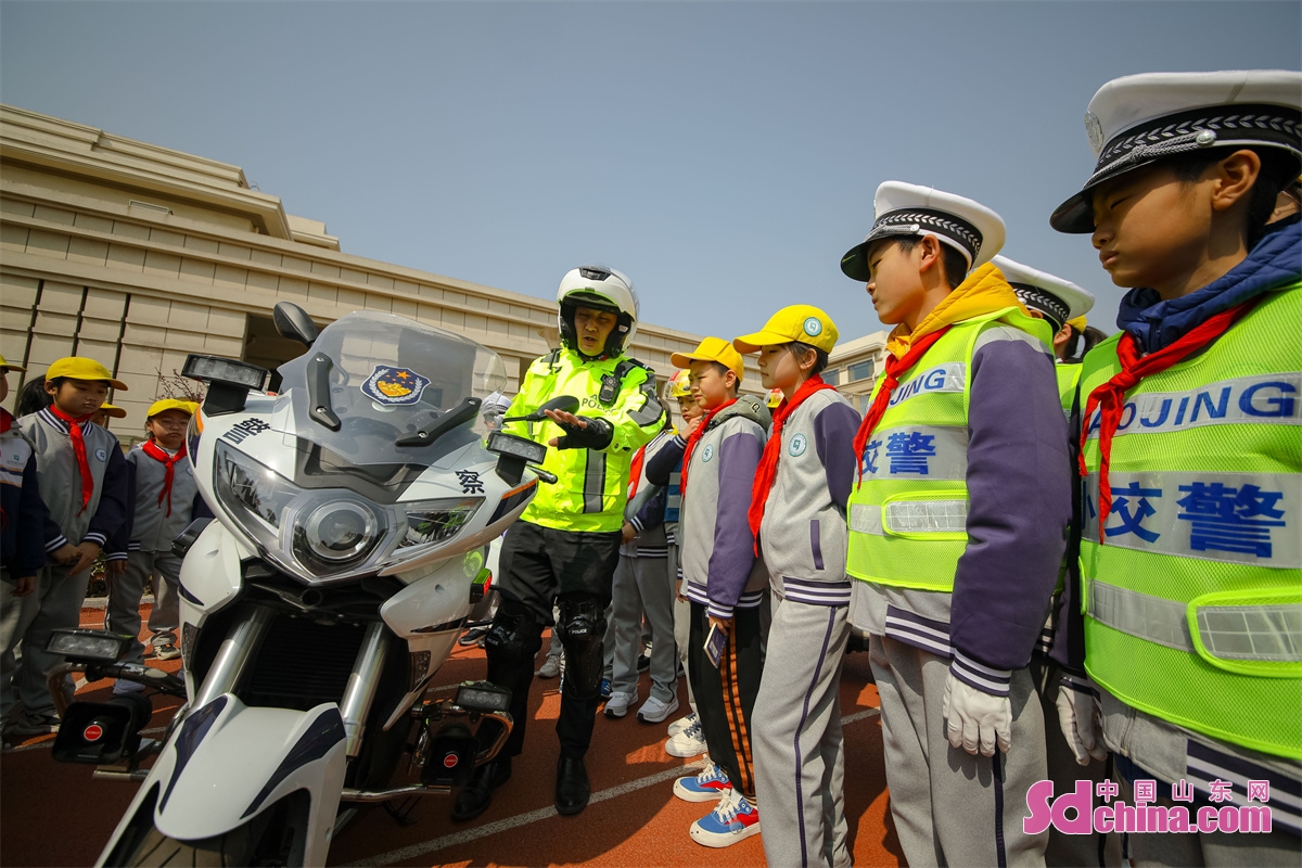  <br/>　　2023年3月27日，在山东省青岛文正小学，交警向小学生讲解警用摩托车。中国山东网发(张鹰 摄)