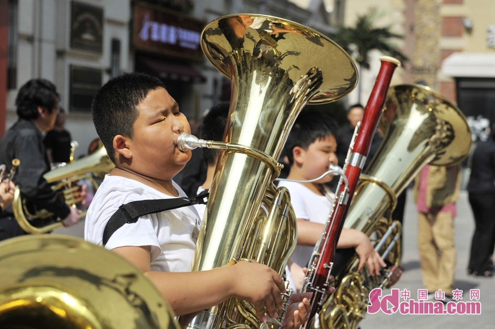 6月7日,学生文艺志愿者在青岛市城阳区鲁邦风情街为市民演奏《欢乐 