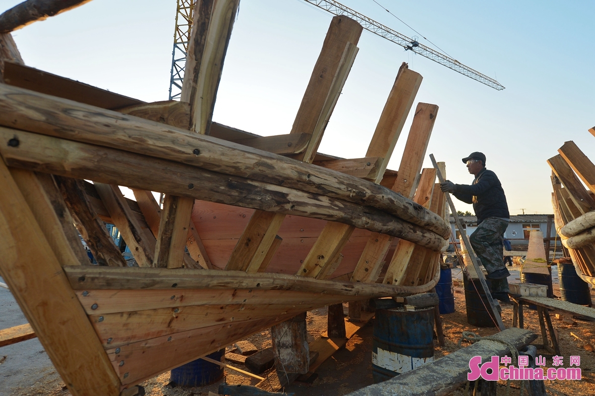 在青島市城陽區紅島街道一處漁港碼頭,一名木船製作手藝人登上漁船